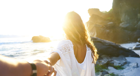A straight couple of both over 40 years old walk in the sandbeach with a beautiful sunset