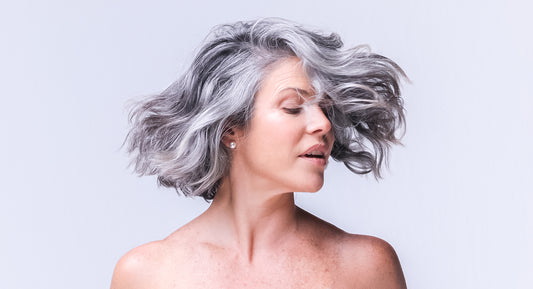A women over 40 years old with gray natural hair is enjoying the hair growth and thickness that the better not younger's products provide her