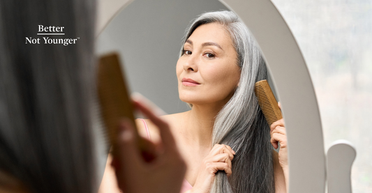 A woman styling her natural gray hair in front if the mirror. If you have gray hair, chances are that you face some of these common problems: