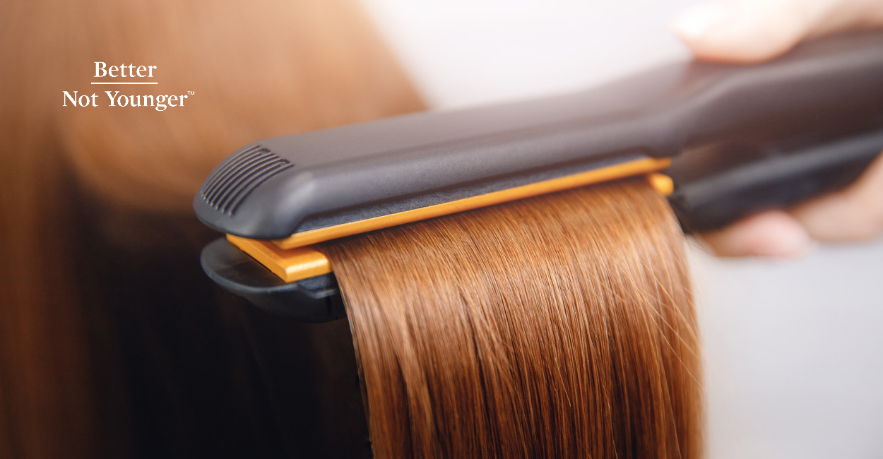 A heat styling tool styling a red hair. 