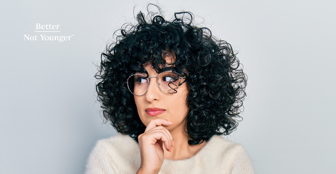 100 sings of aging hair article by Better Not Younger features a woman with curly hair wearing glasses a shed looks like thinking 