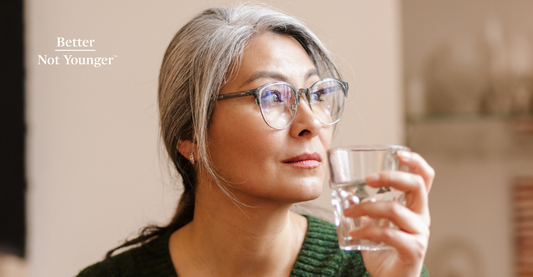 Better Not Younger features on "Can Dehydration Cause Hair Loss?", a woman over 40 with long gray hair holding a glass of water.