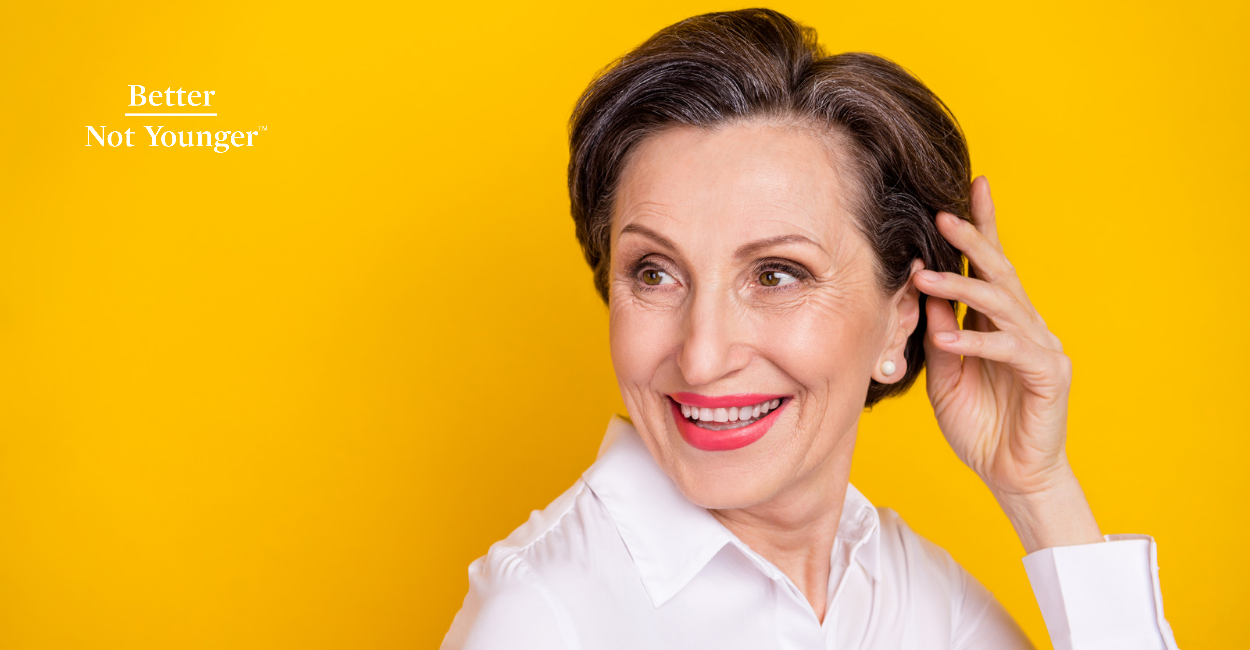 Better Not Younger features a Photo of adorable sweet mature lady wear white clothes arm head looking back empty space smiling isolated yellow color background for the article about using dying hair with dry shampoo in it