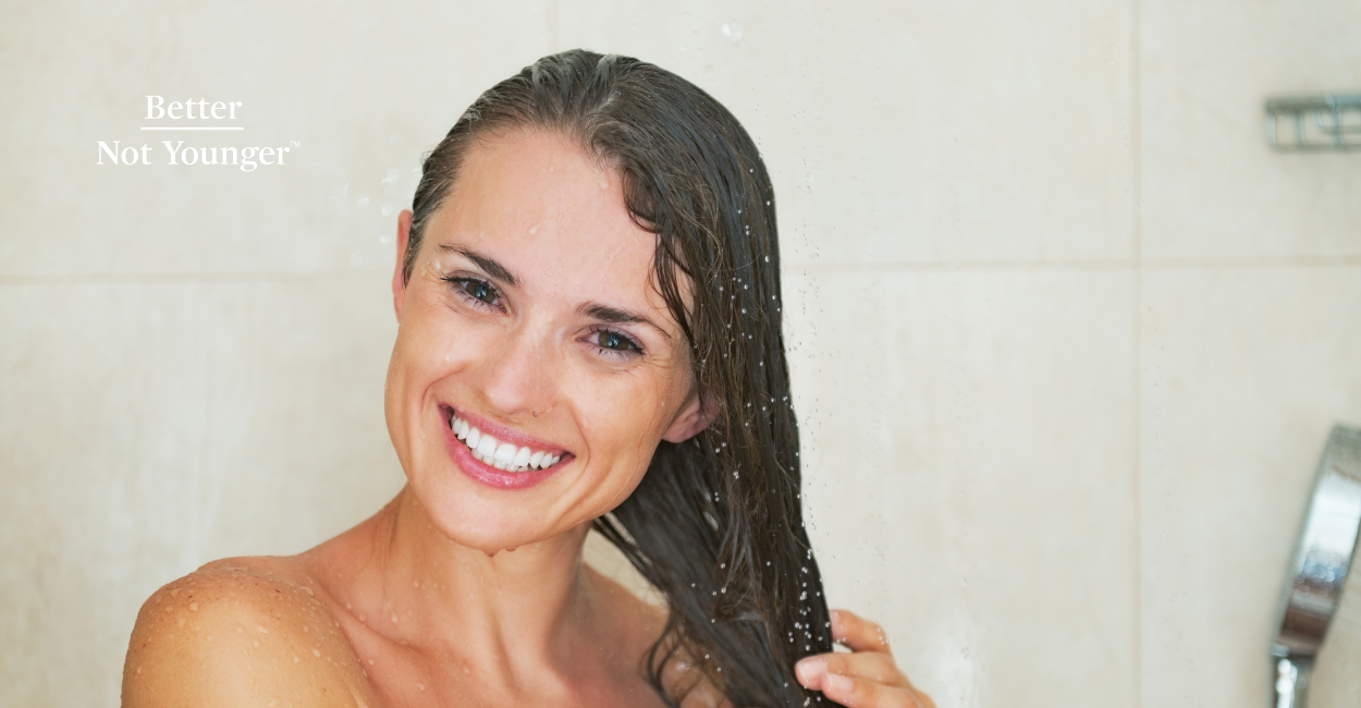 In "Does Water Temperature Affect the Hair Structure?, BNY features a beautiful woman over 40 smiling while holding her hair during her washing hair process in the shower. 
