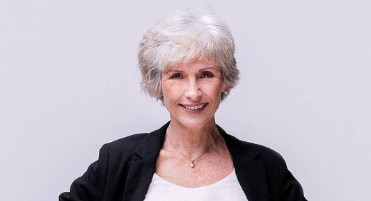 a women over 60 yers old smiles to the camera and feels happy about the thickening benefits of her new volumizing and thickening  shampoo. She has short gray hair. 