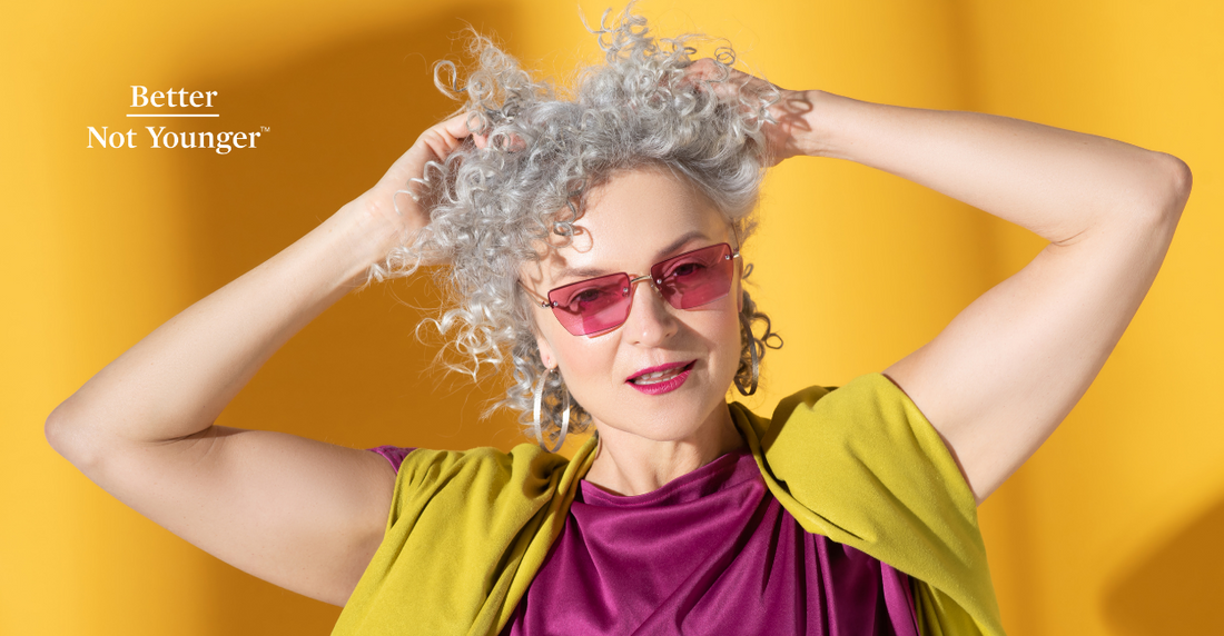 A woman with curly gray hair on a solid yellow background.