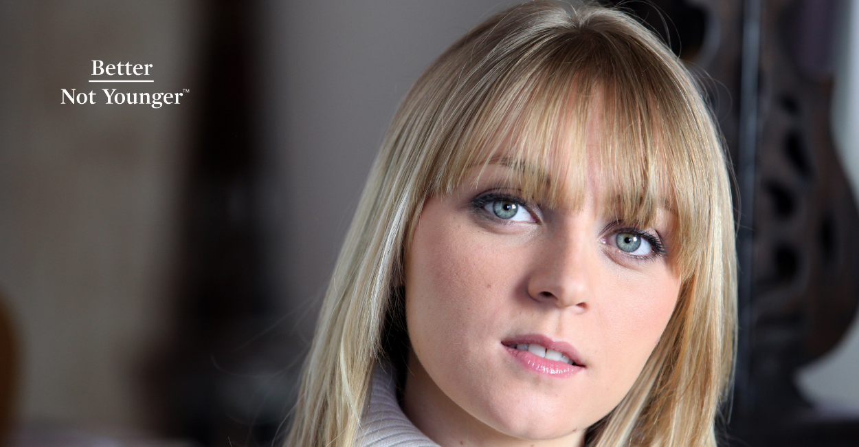 Layered Bangs Are Back in a New Way and Better Not Younger features a blonde woman with blue eyes wearing layered bangs.