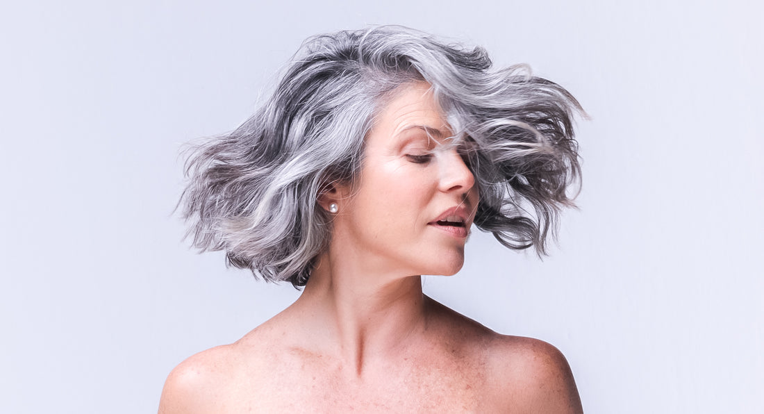 A women over 40 years old with gray natural hair is enjoying the hair growth and thickness that the better not younger's products provide her