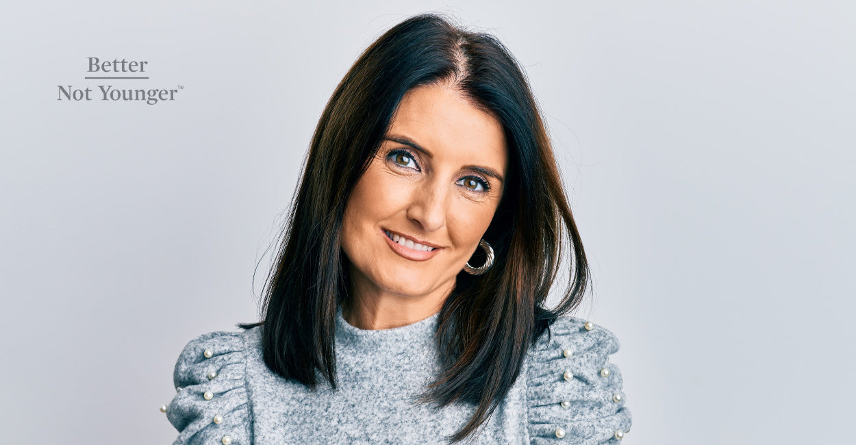 In this article about Finding Balance in Your 50s, BNY features a woman over 50 with light gray hair smiling and with her eyes closed as she looks happy on a pink background.