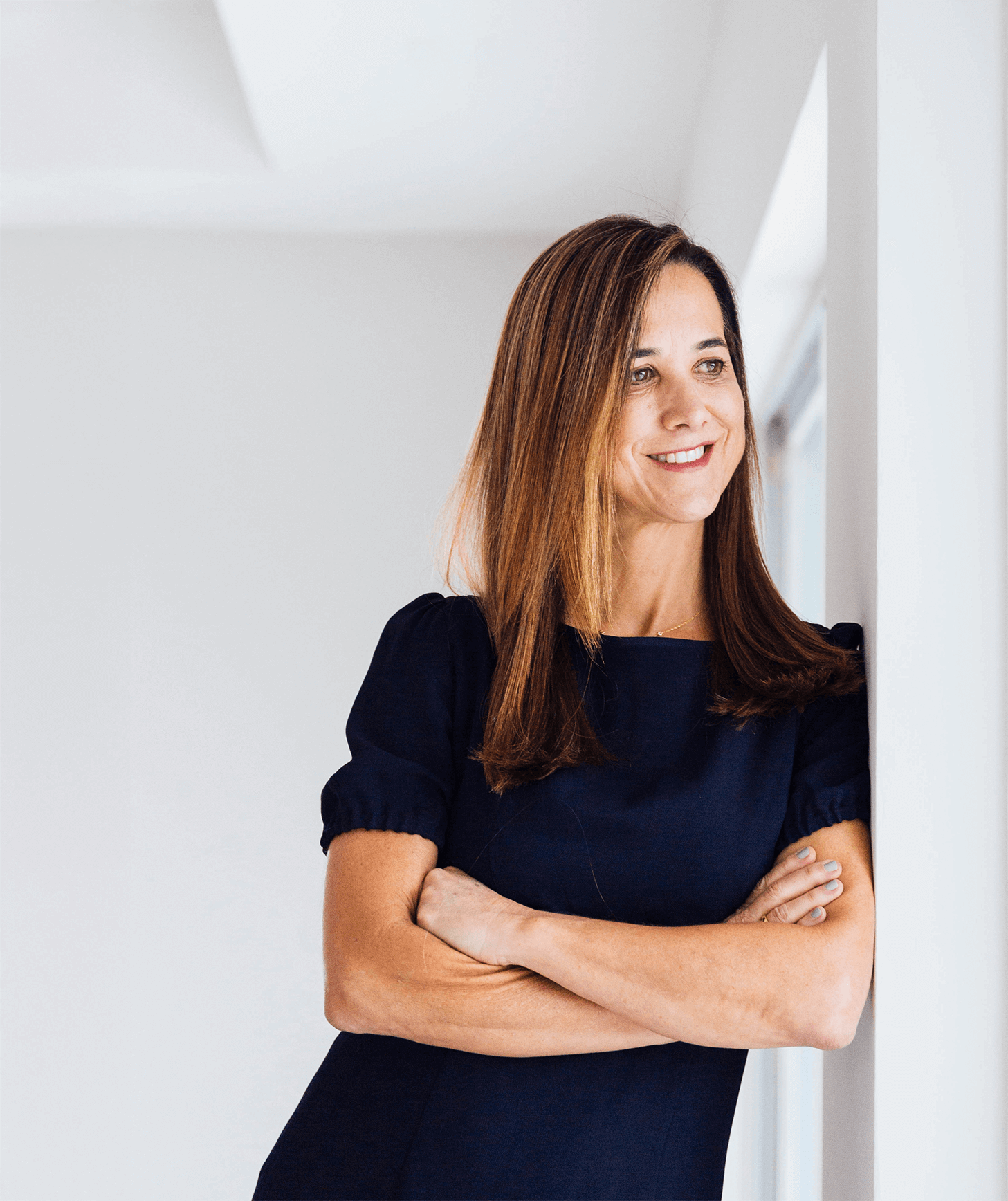 Woman in a navy dress standing against a white wall